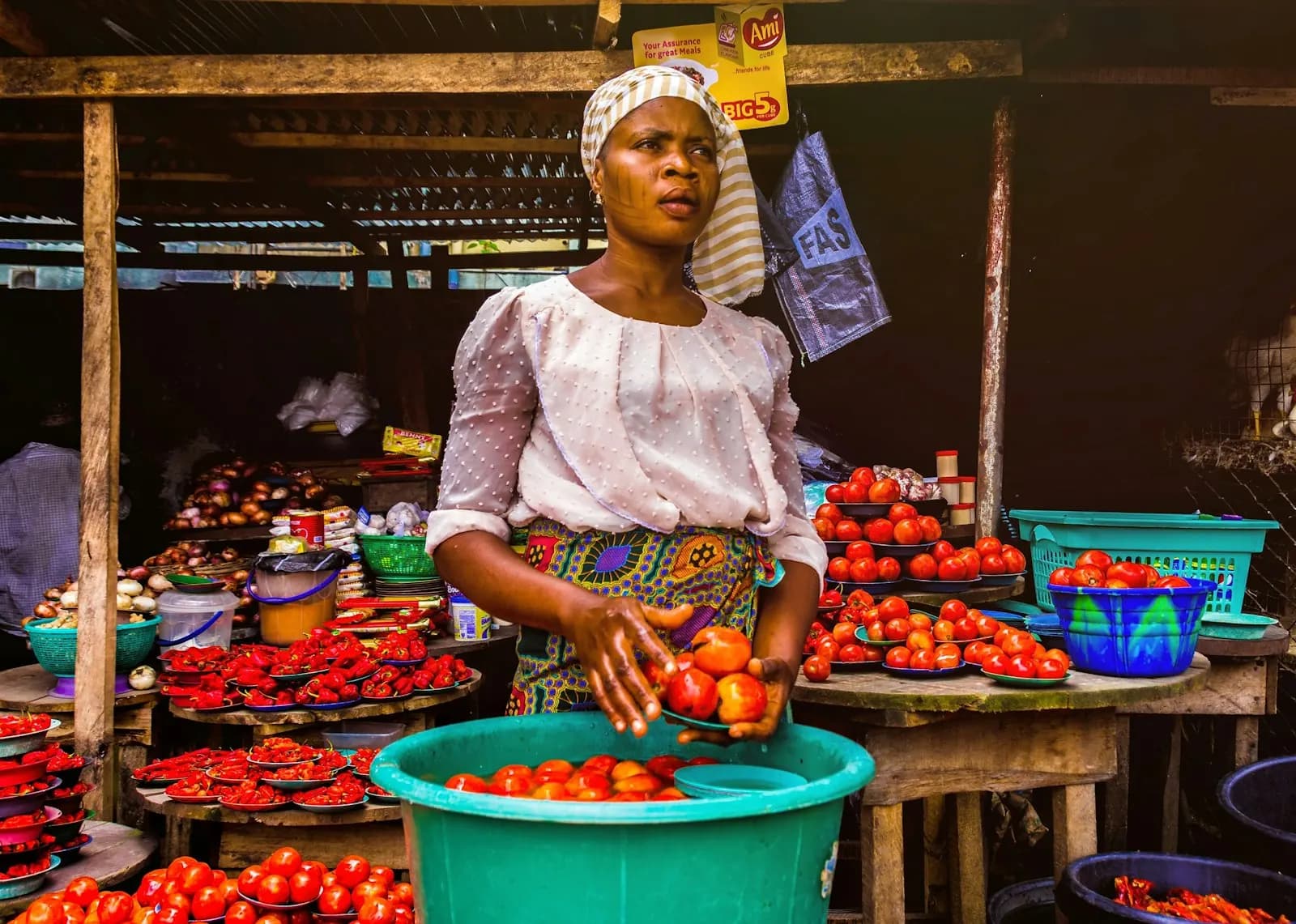 A market trader in Lagos holding tomatoes at her stall